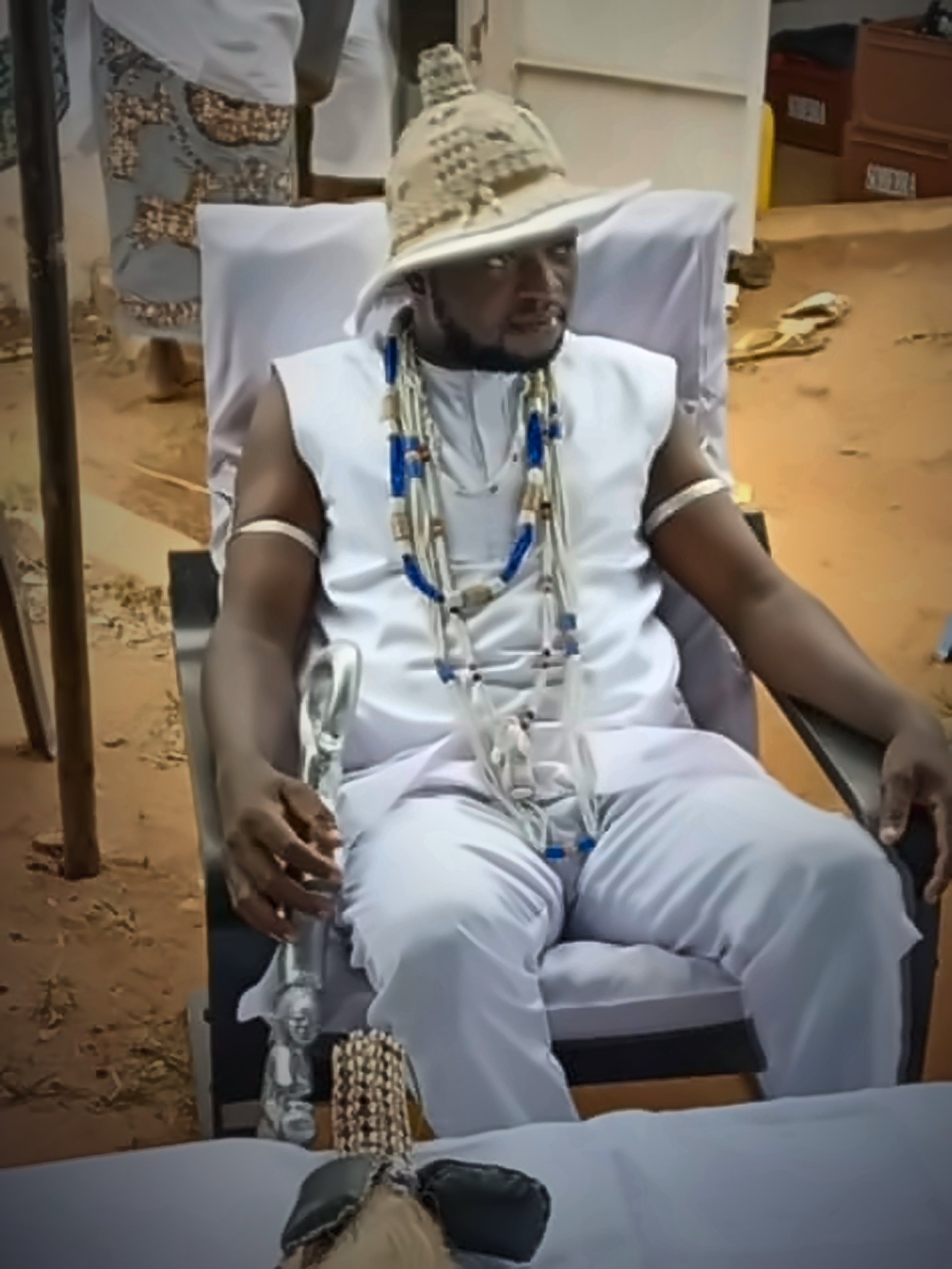 Le Hounnon Djanminnou Hossou assis en tenue blanche de cérémonie, colliers de perles et canne sacrée