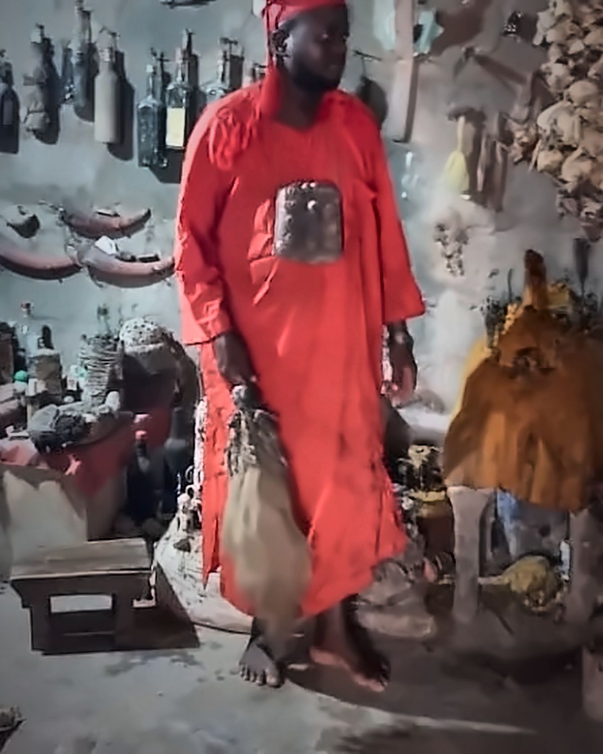 Le Maître Djanminnou Hossou en tenue rouge dans le sanctuaire du couvent, rituel de désenvoûtement
