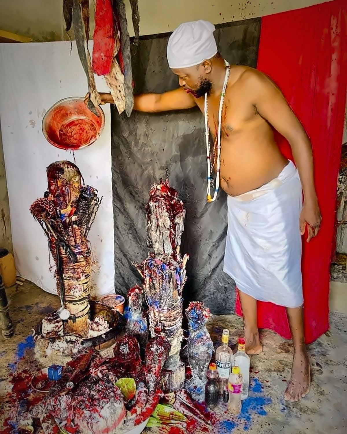 Le Maître Djanminnou Hossou pendant un rituel d'ouverture des portes, offrandes devant les fétiches
